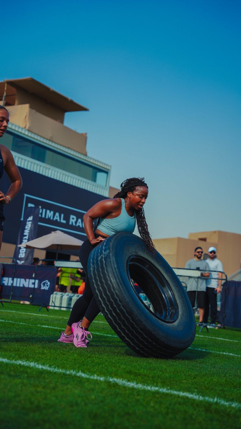 An athlete carrying the tyre past the Primal Race boards