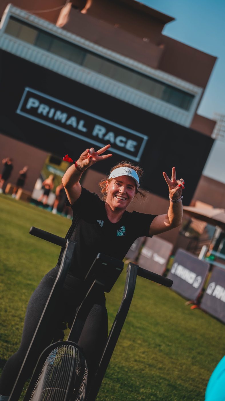 An athlete on the echo bike in front of the Primal Race backdrop
